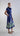 Side view of the sculptural midi dress showing structured bodice, fluid pleated skirt and architectural cuff sleeves.