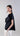 Side view of asymmetric mercerized cotton T-shirt highlighting the sculptural drape and flowing rosette along the neckline.