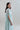 Side view of Psophía SS26 women’s Fluid Midi Dress in lightweight sheer organza, highlighting its airy movement, midi length and embroidered floral appliqué in an elegant summer dress design.