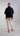 Back view of a fluid shirt with an asymmetrical hem, emphasizing its smooth drape, lightweight fabric and balanced contemporary silhouette.