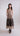 Front view of sleeveless V-neck dress with gathered waist and contrasting floral appliqué on midi skirt